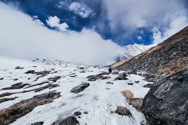 Hiker crossing high mountain terrain protected by activity top-up insurance for trekking.