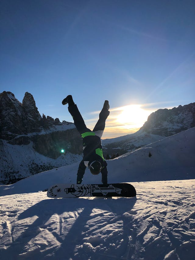 Snowboarder attempting a freestyle trick on a snow-covered alpine slope, an activity typically covered by snowboard holiday insurance