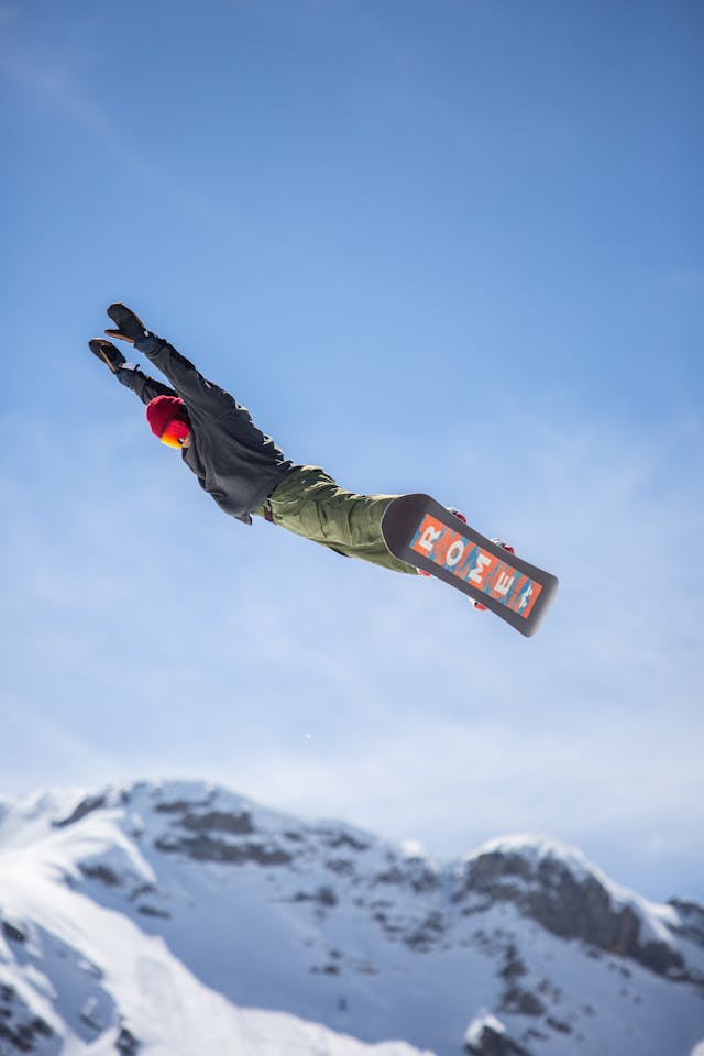 Snowboarder performing an aerial jump above a snowy mountain slope, demonstrating the importance of snowboard holiday insurance